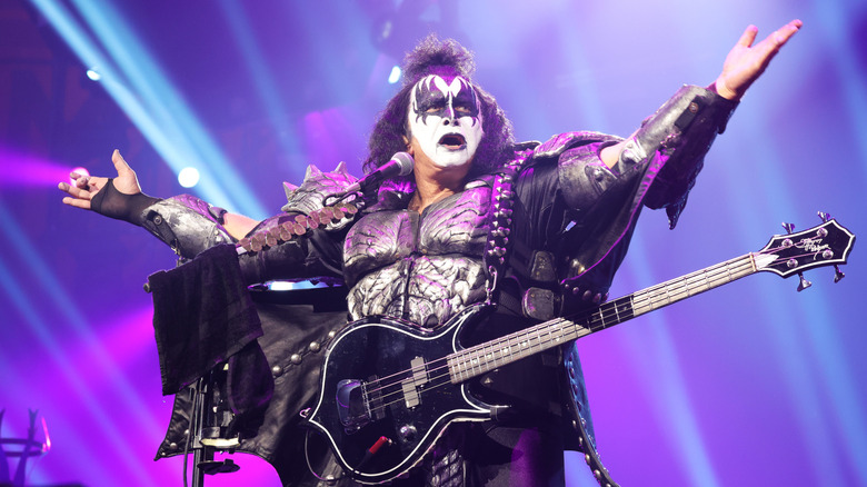 Gene Simmons in Kiss costume with guitar arms outstretched on stage
