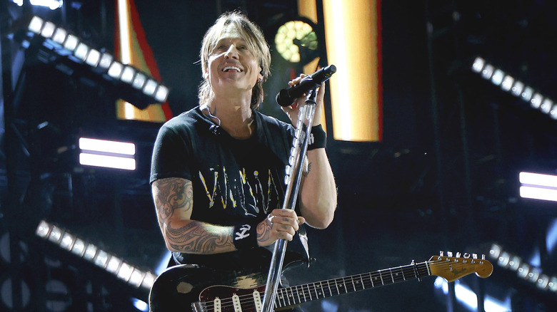 Keith Urban onstage with microphone and guitar