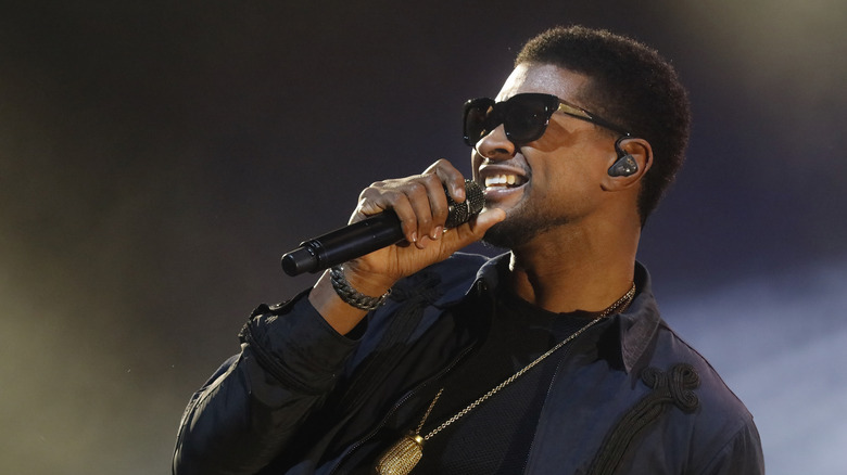 Usher singing into a microphone on stage.