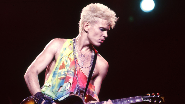 Billy Idol playing guitar on stage in the 1980s