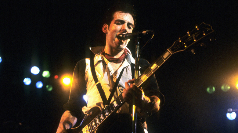 The Clash's Mick Jones playing guitar and singing