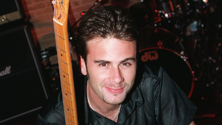 Jamie Walters smiling while posing with guitar