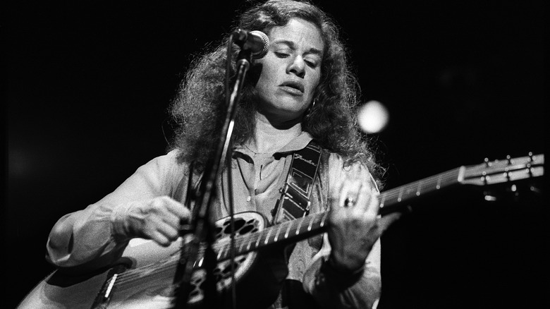 Carole King playing guitar on stage