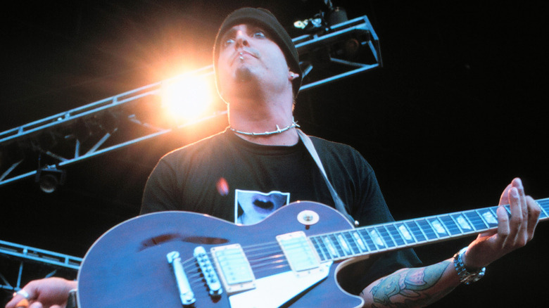 Wayne Swinny holding his guitar onstage with bright ligh