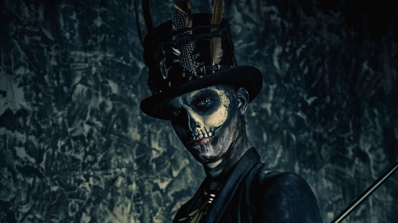 Man with black feathered hat and skull face paint