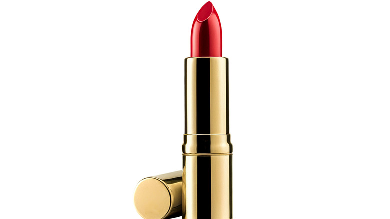 closeup red lipstick in gold-toned case, white background.