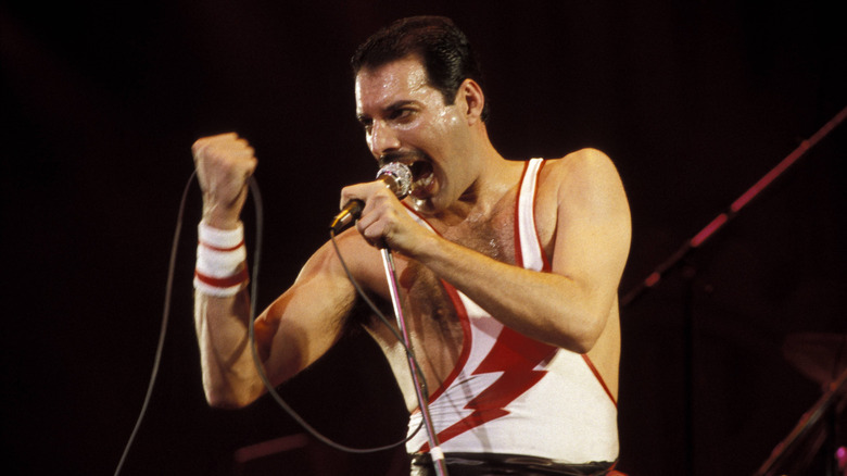 Freddie Mercury onstage with microphone in lightning strike vest