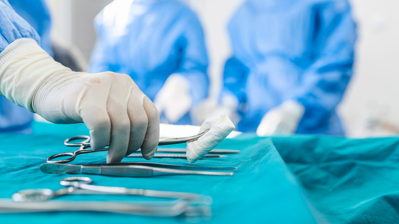 gloved hand picking up surgical tools