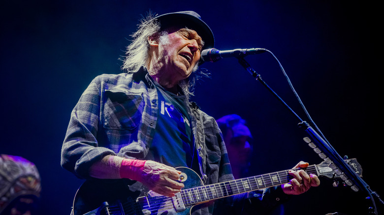 Neil Young on stage in 2019 singing and playing guitar.