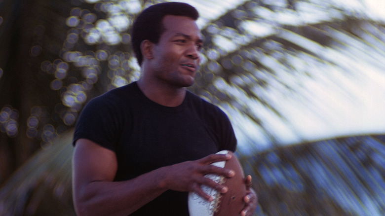 Jim Brown smiling holding football black shirt