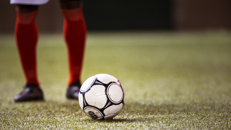 Soccer player standing next to ball