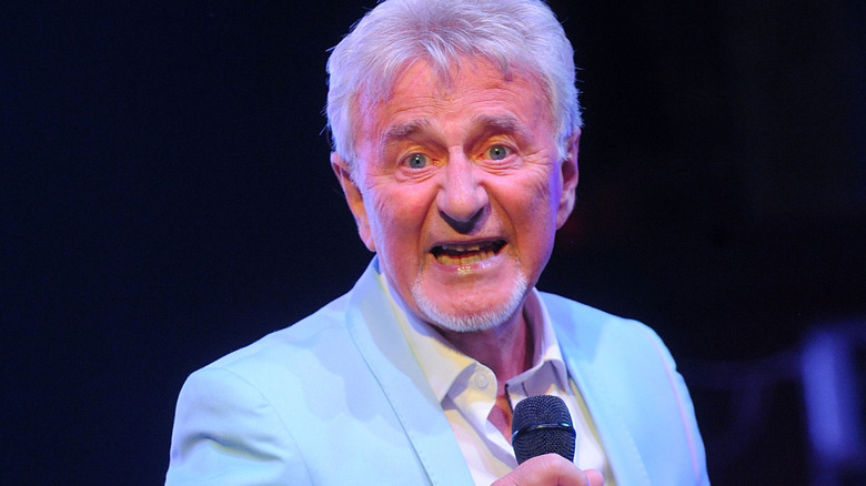 Tony Burrows singing on stage wearing a baby blue suit
