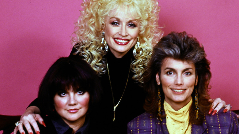 Dolly Partton, Emmylou Harris, and Linda Ronstadt smiling together