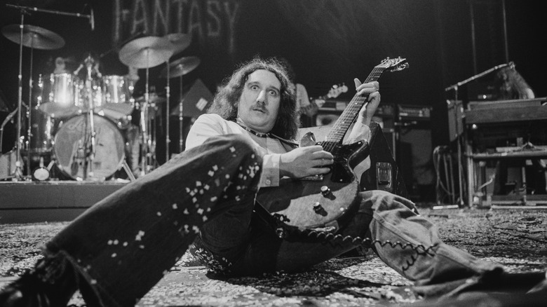 Uriah Heep guitarist Mick Box laying on stage with guitar