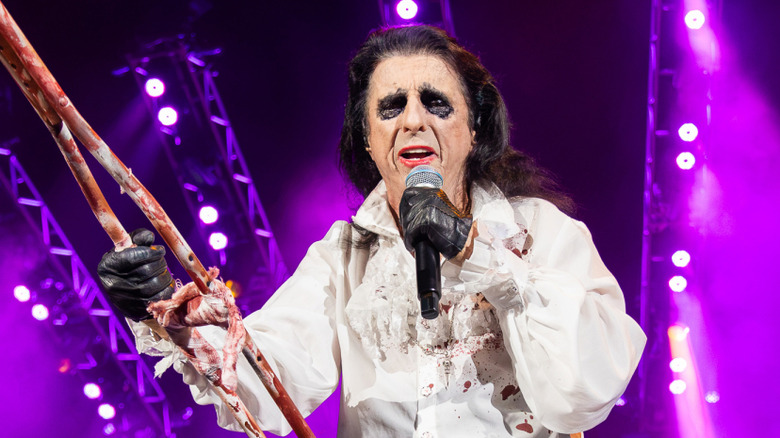 Alice Cooper onstage with cane and microphone