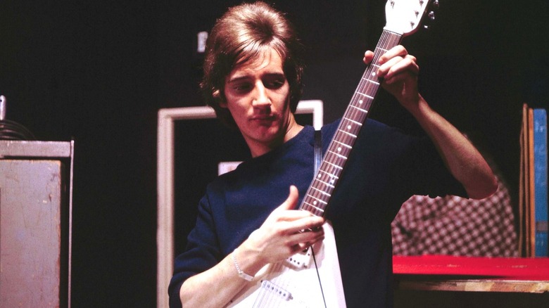 Rod Stewart playing a guitar by some amps