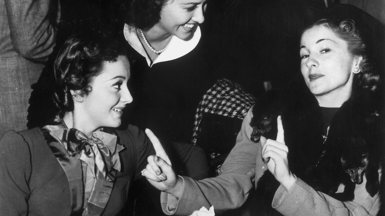 Joan Fontaine and Olivia de Havilland talking while seated