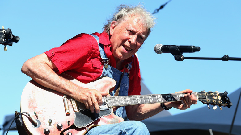 Elvin Bishop playing guitar in front of a microphone