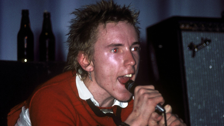 johnny rotten yelling into microphone in front of speaker