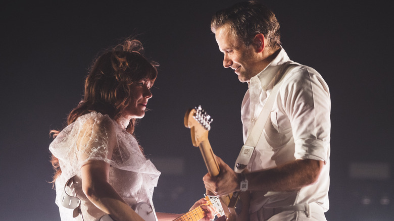 jenny lewis and ben gibbard dressed in white playing guitars during postal service show