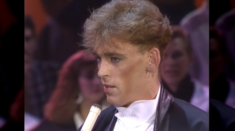 Jimmy McShane in suit being interviewed on stage