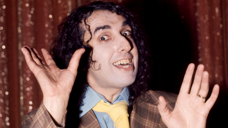 Tiny Tim smiling and holding up hands