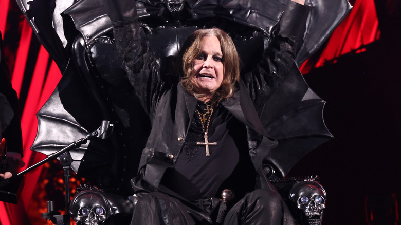Ozzy Osbourne triumphantly raising hands in throne