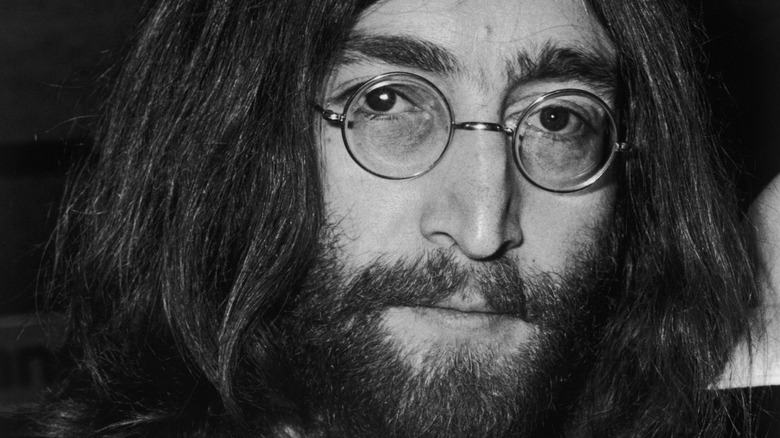 John Lennon with long hair and round glasses