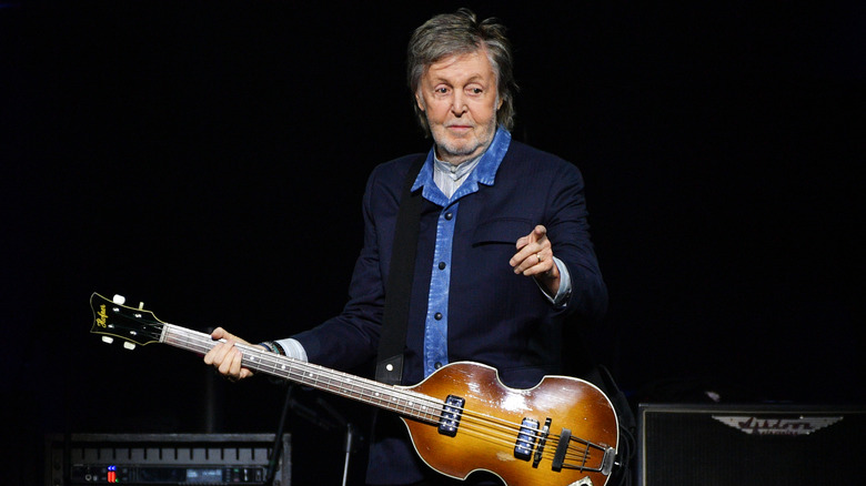 Paul McCartney holding a guitar and pointing