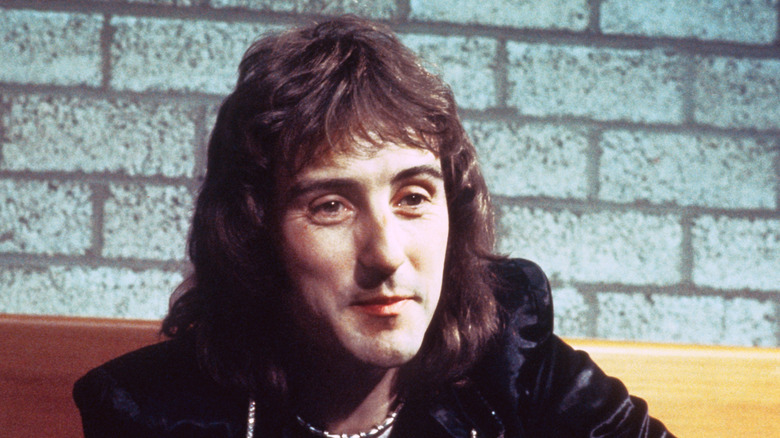Photo of guitarist Denny Laine in front of a brick wall