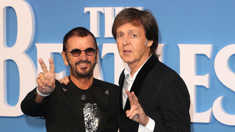 Ringo Starr posing with Paul McCartney in front of The Beatles logo