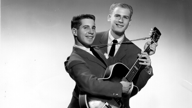 Paul Simon holding guitar with Art Garfunkle