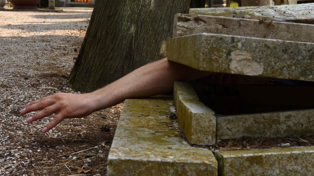 Hand extending out of grave site