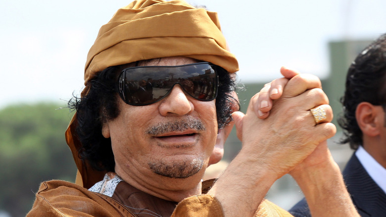 Gaddafi wearing sunglasses with hands clasped 