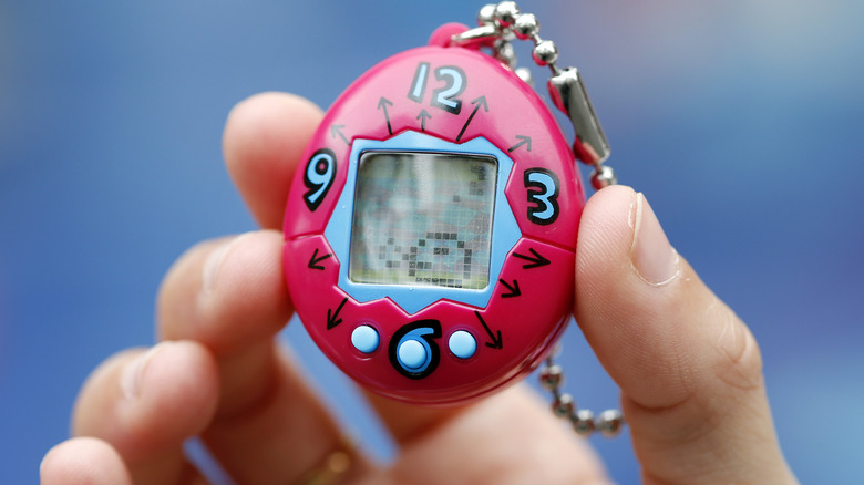 hand holding red Tamagotchi