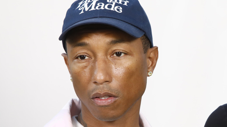 Pharrell Williams in blue cap unsmiling