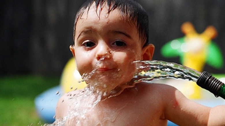 Kid drinking water from a hose