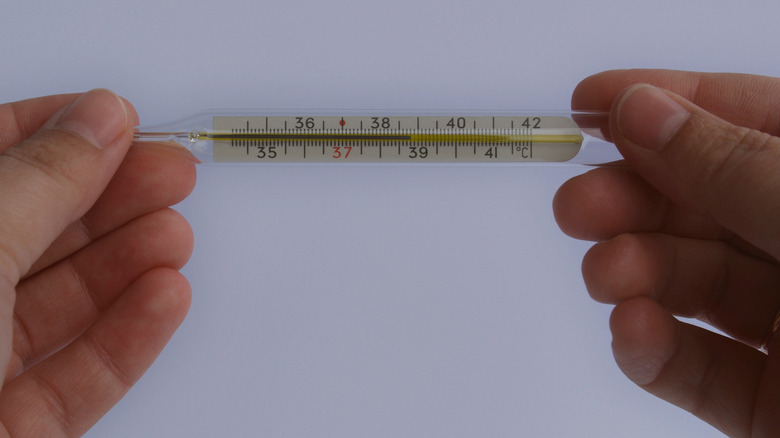 Hands holding old mercury thermometer