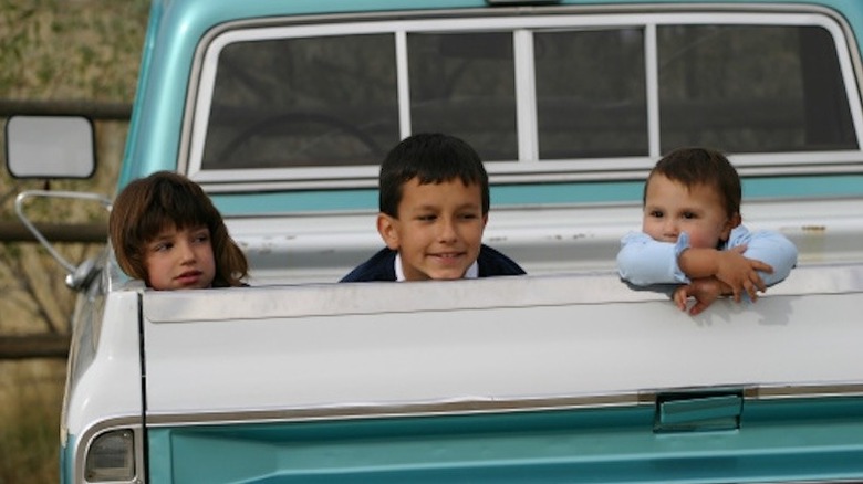 Three kids in the back of a pickup truck