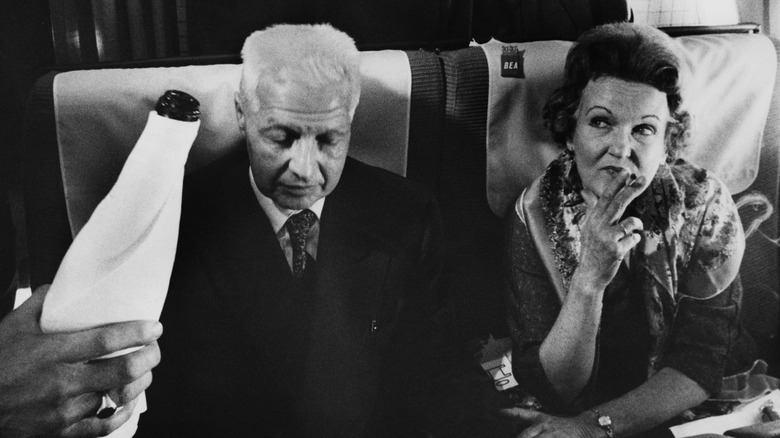 Elder Russian spies drinking and smoking on an airplane