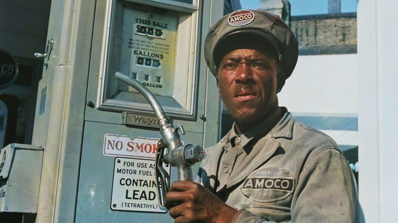 Gas station attendant holding pump and using leaded gas