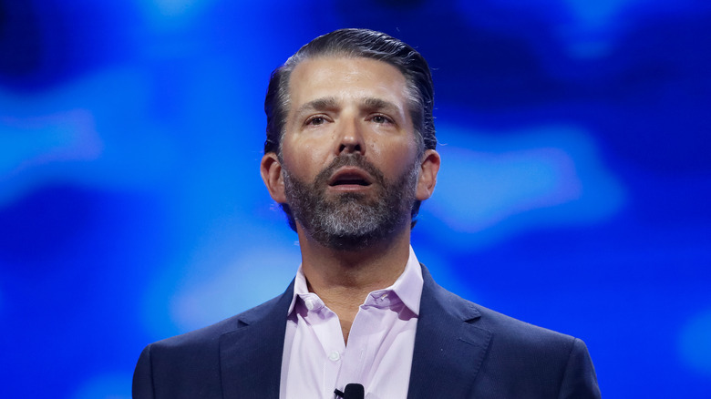 Donald Trump Jr. suit beard talking blue background