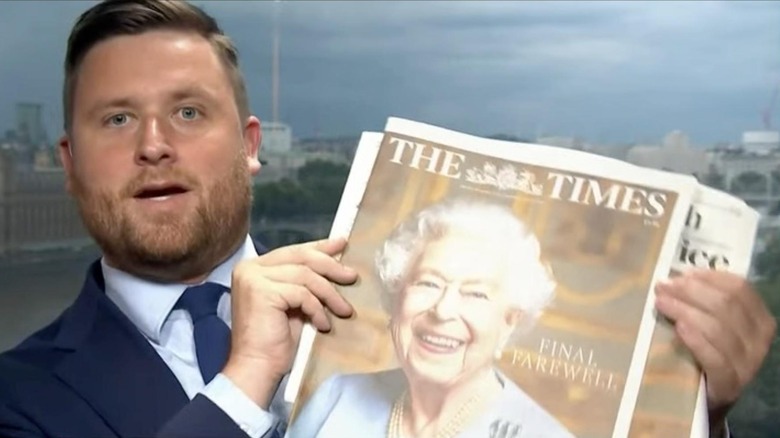 Photo of man holding newspaper with queen elizabeth's photo 