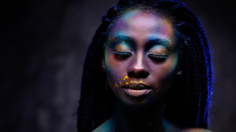Black woman with serious expression in colorful makeup