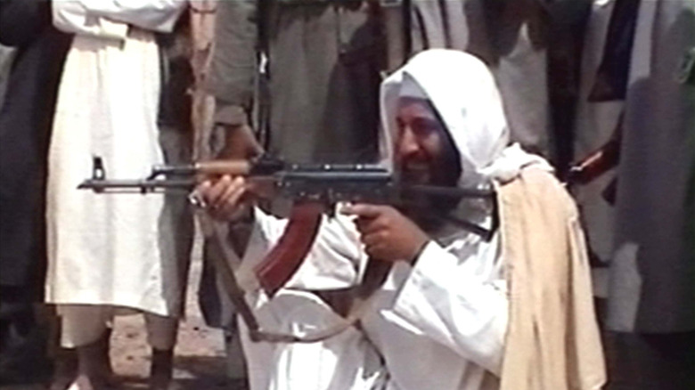 Osama Bin Laden with Ak27 crouching crowd of people