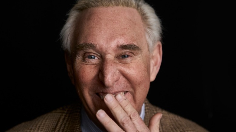 Roger Stone smirking with hand over face