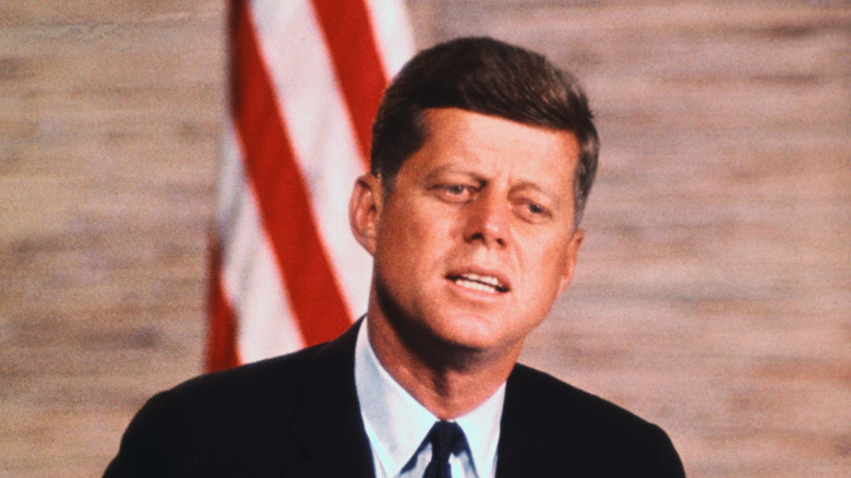 John F. Kennedy speaks in front of American flag