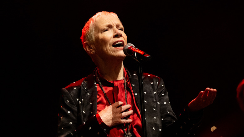 Annie Lennox singing on stage in black and red suit and shirt