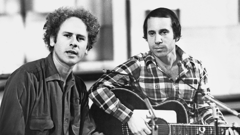 Black and white photo of Art Garfunkel and Paul Simon holding a guitar singing together