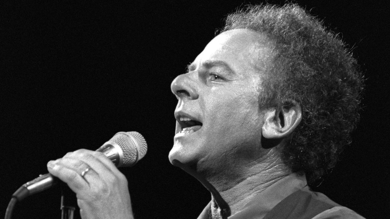 Black and white photo of singer Art Garfunkel holding a microphone during a Simon and Garfunkel reunion performance in 1993